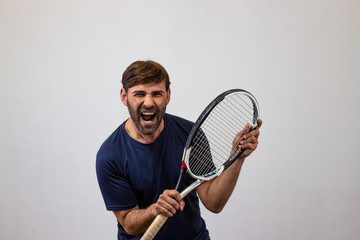 Portrait of handsome young man playing tennis holding a racket with brown hair energic, looking at...