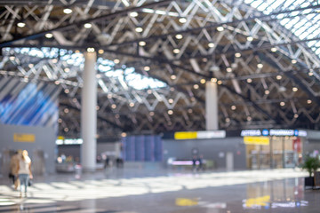 Blurred beautiful bokeh background: blurred people, traveller silhouette is walking in the airport departure hall