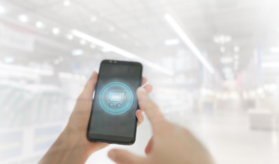 Shopping basket on a mobile phone screen. Woman Hand holding mobile phone on Supermarket blur background