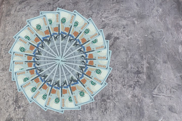 Artistic pattern made from dollar bills Snowflake, flower or star on wooden table. Top view.