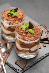 Classic tiramisu dessert in a glass on dark concrete background