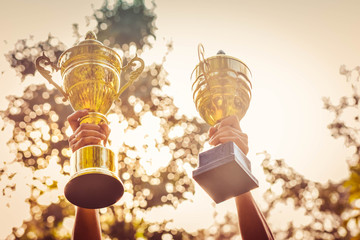 Winner holding golden trophy against nature background