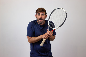 Portrait of handsome young man playing tennis holding a racket with brown hair stressed, looking at...