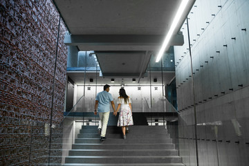 Young family walking inside the modern building in high-tech architecture style. Fashion couple...