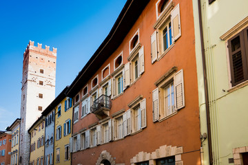 Fototapeta na wymiar tower and colorful apartments in shopping street Trento, Italy