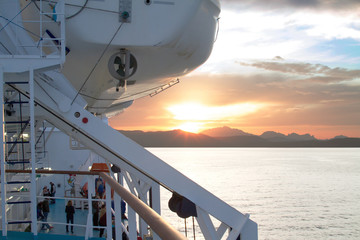 Sunrise on the Sardinian sea coast with intense orange color seen from the sea on the ferry that is...