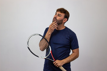 Portrait of handsome young man playing tennis holding a racket with brown hair resentment, facing...