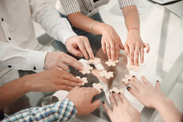 close up. business team sitting at the table and collecting puzzle