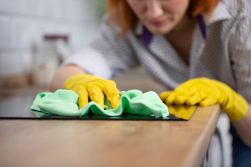 Woman cleaning induction top, hand in yellow rubber glove polish stove cooktop, closeup, no face....