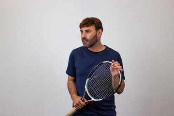 Portrait of handsome young man playing tennis holding a racket with brown hair looking pride,...