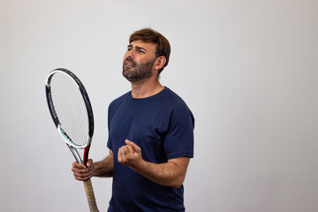 Portrait of handsome young man playing tennis holding a racket with brown hair regretful, facing...