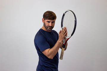 Portrait of handsome young man playing tennis holding a racket with brown hair vulnerable, their...