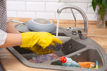 Close up hands of woman washing dishes in kitchen