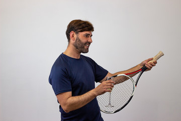 Portrait of handsome young man playing tennis holding a racket with brown hair giving a thumbs up, facing forwards and looking at the side. Isolated on white background.