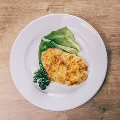 chicken fillet in cheese and lettuce on a white plate