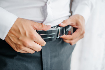 the guy fastens the belt on black trousers
