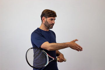 Portrait of handsome young man playing tennis holding a racket with brown hair covering the eyes,...
