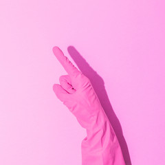 Fashion creative concept with hand in pink rubber glove, showing gesture. Symbol of point. Aesthetic abstract minimalism.