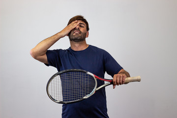 Portrait of handsome young man playing tennis holding a racket with brown hair covering the ears,...