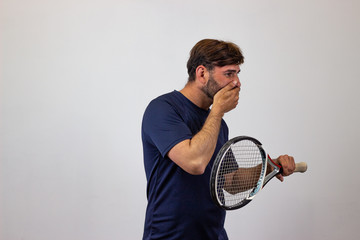 Portrait of handsome young man playing tennis holding a racket with brown hair pointing at the...