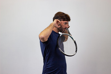 Portrait of handsome young man playing tennis holding a racket with brown hair giving a punch, facing forwards and looking at the side. Isolated on white background.