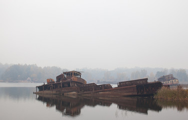 Fototapeta premium Old sunken ship in water in a foggy day