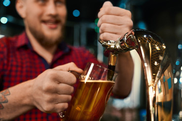 Male barmen poring beer in pint in pub