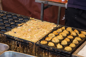 Cooking takoyaki (Octopus ball), famous Osaka snack, on hot pan