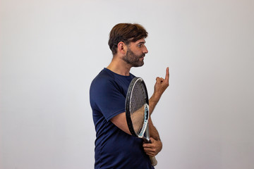 Portrait of handsome young man playing tennis holding a racket with brown hair holding up three...