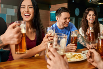 Company laughing and joking while drinking tasty beer in pub