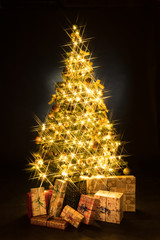 Gifts and golden Christmas tree bokeh in a black background