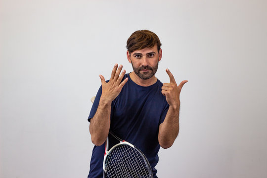 Portrait of handsome young man playing tennis holding a racket with brown hair holding up nine fingers, looking at the camera. Isolated on white background.