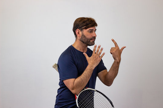 Portrait of handsome young man playing tennis holding a racket with brown hair holding up nine fingers, facing forwards and looking at the side. Isolated on white background.
