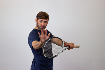 Portrait of handsome young man playing tennis holding a racket with brown hair holding an invisable object, their back facing the camera and looking at the camera. Isolated on white background.