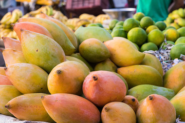 Pile of organic mangoes and other fruits in market, background