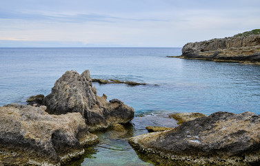 cliffs by the sea in the foreground and large cliff in the background, overcast weather