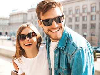 Smiling beautiful girl and her handsome boyfriend in casual summer clothes. Happy cheerful family having fun on the street background in sunglasses.