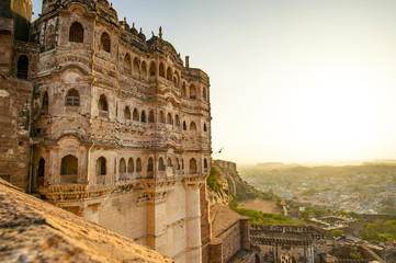 Fototapeta premium Wspaniały widok na starożytny fort Mehrangarh podczas pięknego zachodu słońca z niebieskim miastem Jodhpur w tle, Rajasthan, Indie. Mehrangarh (Fort Mehran) to jeden z największych fortów w Indiach.
