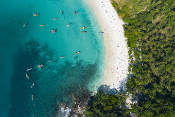 Fototapeta na wymiar View from above, stunning aerial view of a beautiful tropical beach with white sand and turquoise clear water, long tail boats and people sunbathing, Freedom beach, Phuket, Thailand.