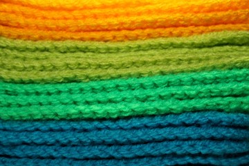 Fototapeta na wymiar Colorful yellow, green and blue design background of knitted woolen elements in a pale