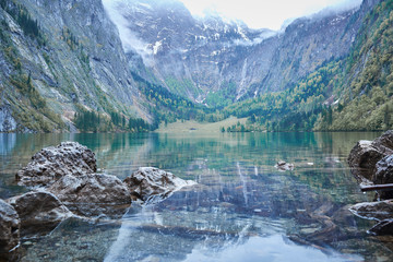 recflecting lake konigsee with view at distant waterfall rothbachfall