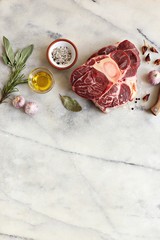 Fototapeta na wymiar Raw cut veal or beef shanks on marble cutting board. Overhead view, copy space