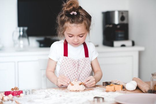Pretty kid girl 3-4 year old making cake with almond cooking at kitchen closeup. Childhood.