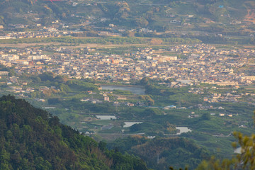 Looking down on a small town in green valley as late afternoon sun cast light on buildings