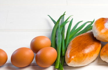  patties with egg and onions on a white wooden background. sweet cakes with filling. green onions