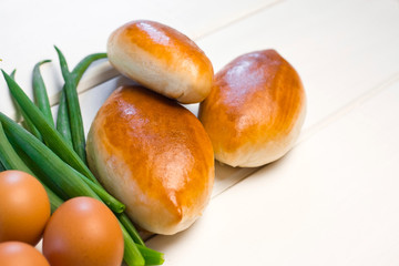  patties with egg and onions on a white wooden background. sweet cakes with filling. green onions
