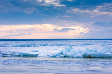 Beach in wintertime. Frozen sea, evening light and icy weather on shore like fairy tale country. Winter on coast. Blue sky, white snow, ice covers the land.