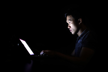 Young programer student run assignment with laptop alone at midnight in the dark room