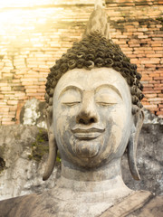 Head portrait of ancient Buddha statue of Buddhism with sun flare