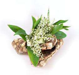 Bouquet of lily of the valley is placed in bast like as in a vase on a white background